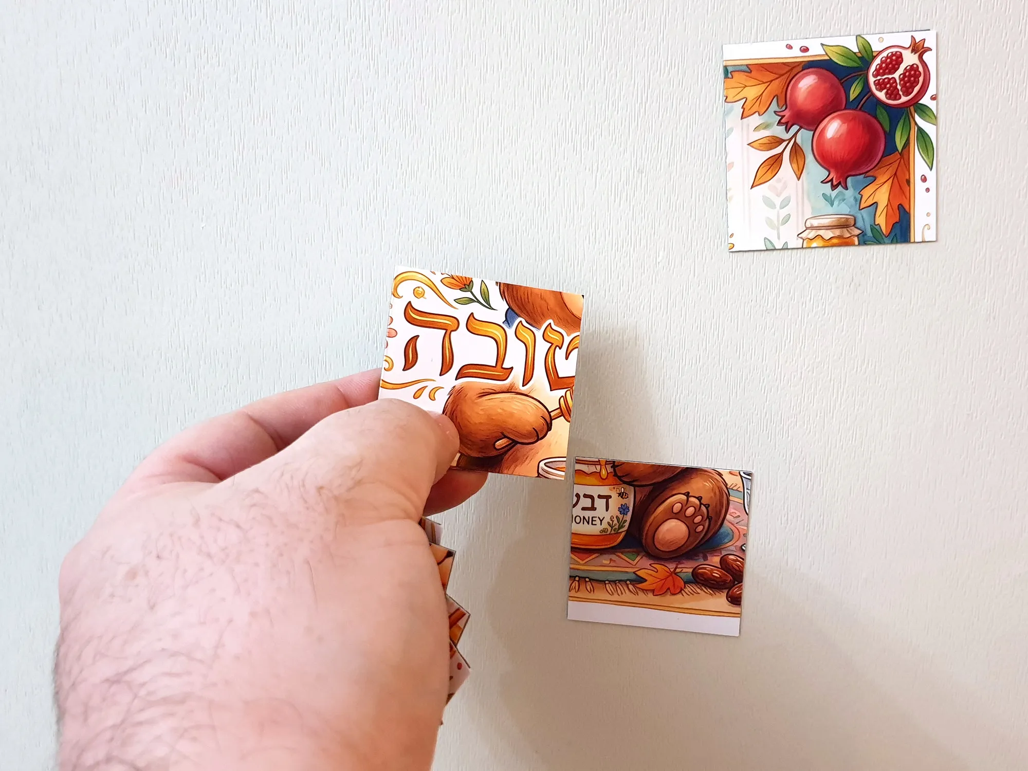 איור של דוב חמוד יושב מול צנצנת דבש עם כף דבש, מוקף ברימונים, תפוחים וחלה, ומעליו הכיתוב שנה טובה - זווית נוספת
